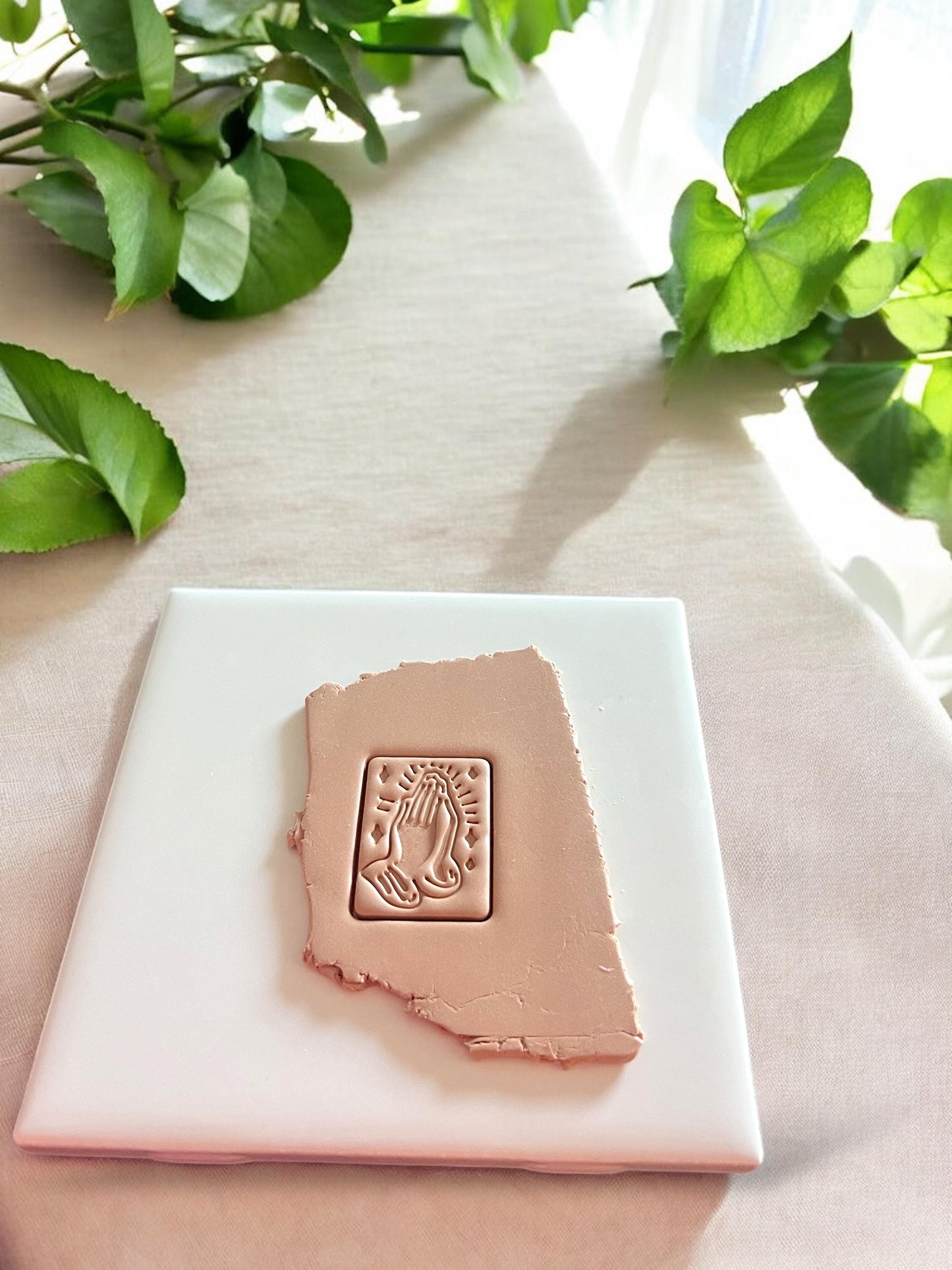 A slab of polymer clay with a praying hands design cut using a detailed rectangular polymer clay cutter for earring making