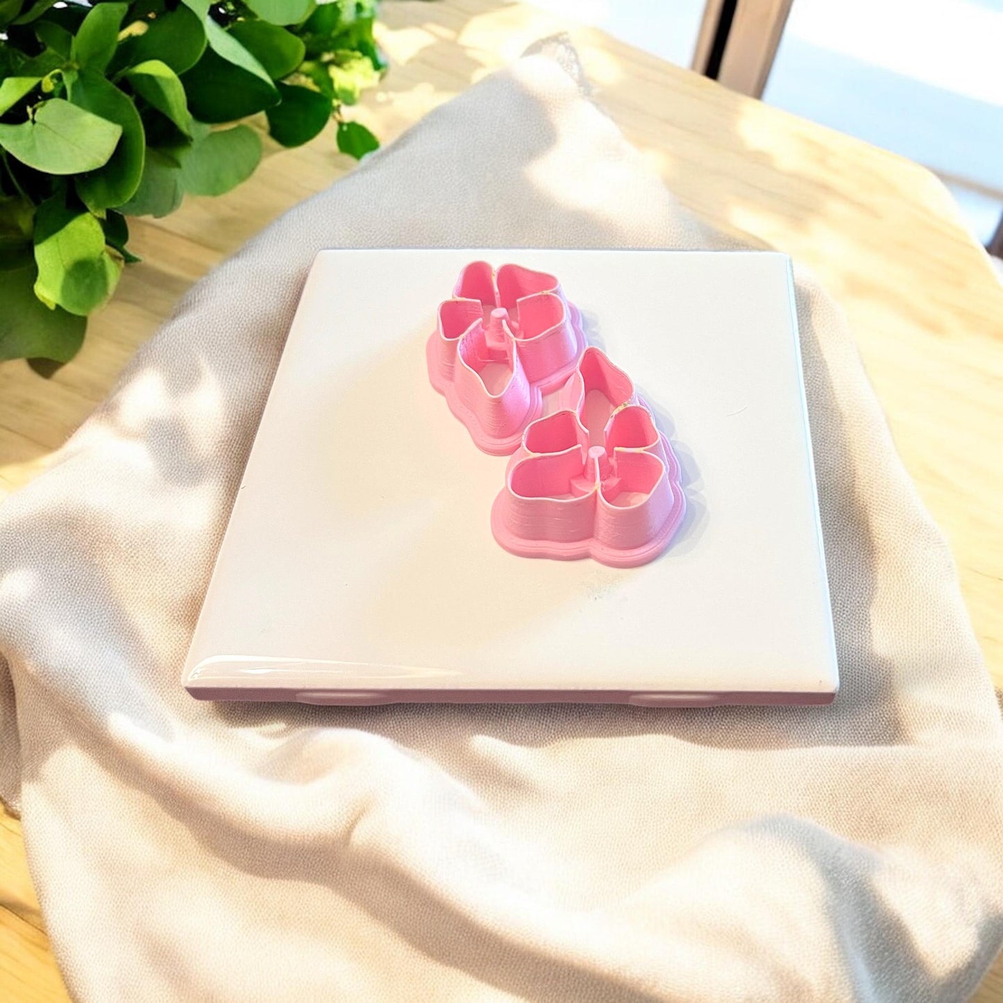 A close-up view of two pink interlocking flower polymer clay cutters, ideal for floral earring designs