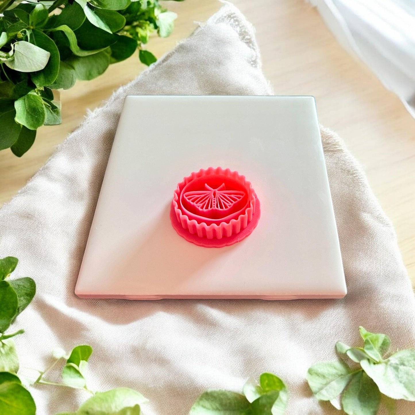 A pink butterfly clay cutter with a scalloped circular edge, perfect for dangle earrings or pendants