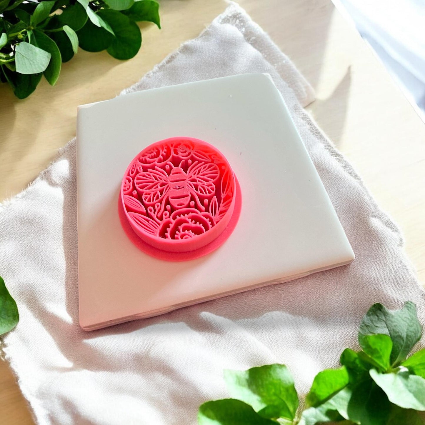 A close-up of the pink 3D printed polymer clay cutter with intricate bee and floral patterns for nature-inspired clay designs