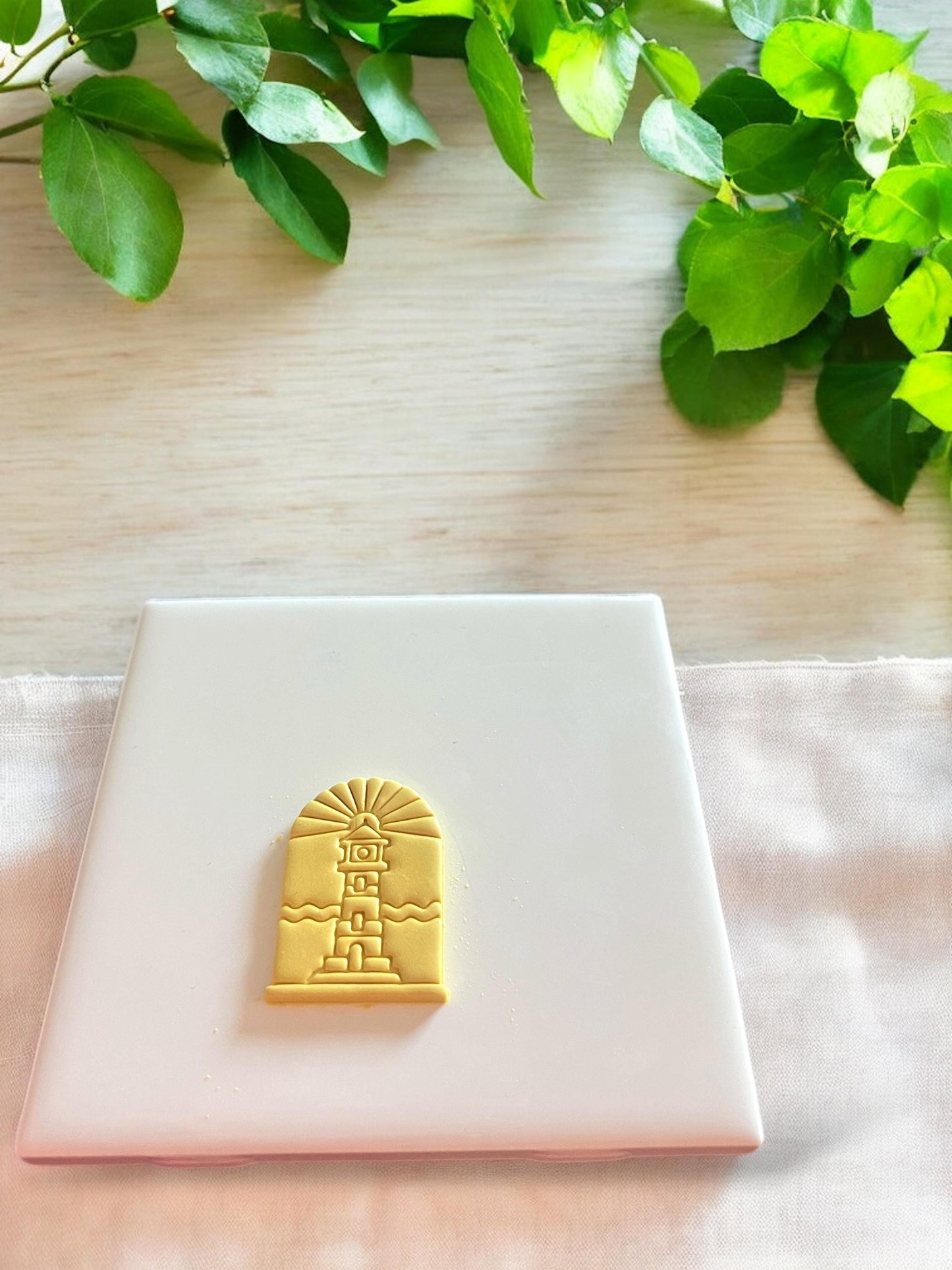 Finished clay piece showing a lighthouse within an arch, ideal for summer jewelry designs like pendants or drop earrings