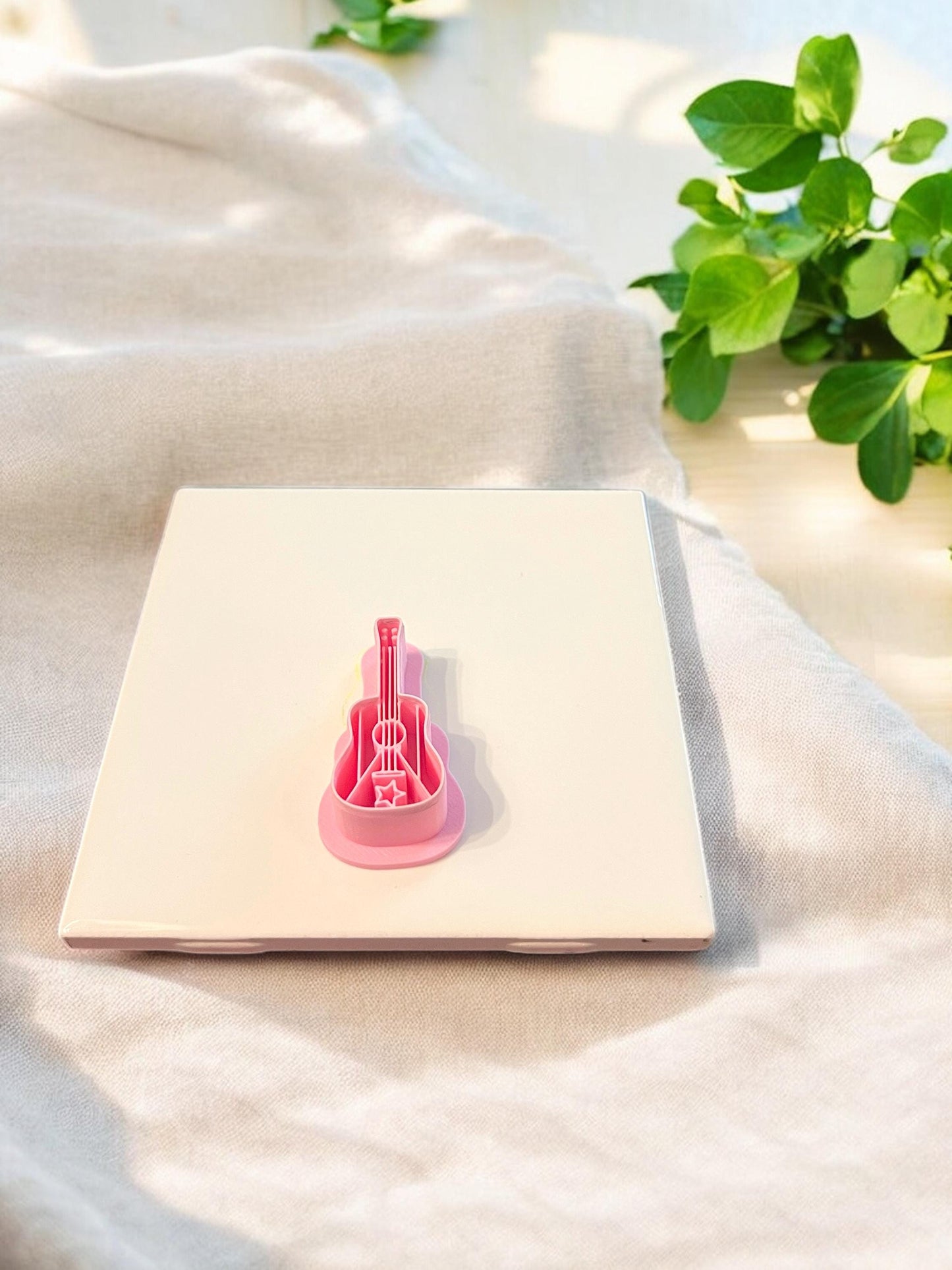 A close-up of the pink guitar-shaped polymer clay cutter featuring cultural tropical styling for handmade statement earrings