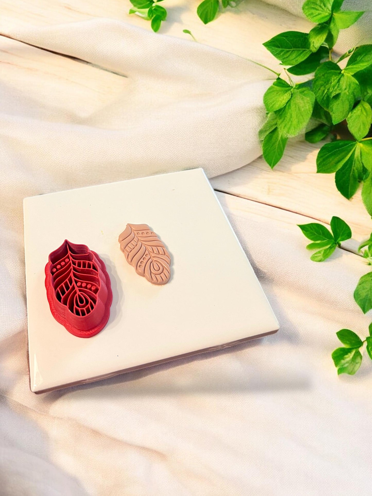Finished boho leaf clay design shown with the matching red polymer clay cutter used to create the textured shape