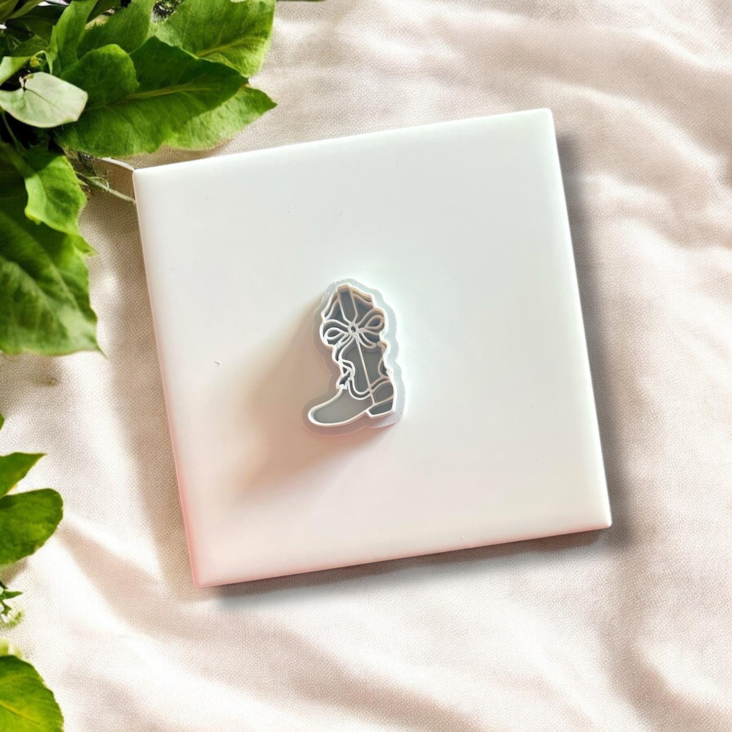 Completed earrings made from the cowboy boot cutter with bow, displayed on a neutral background.