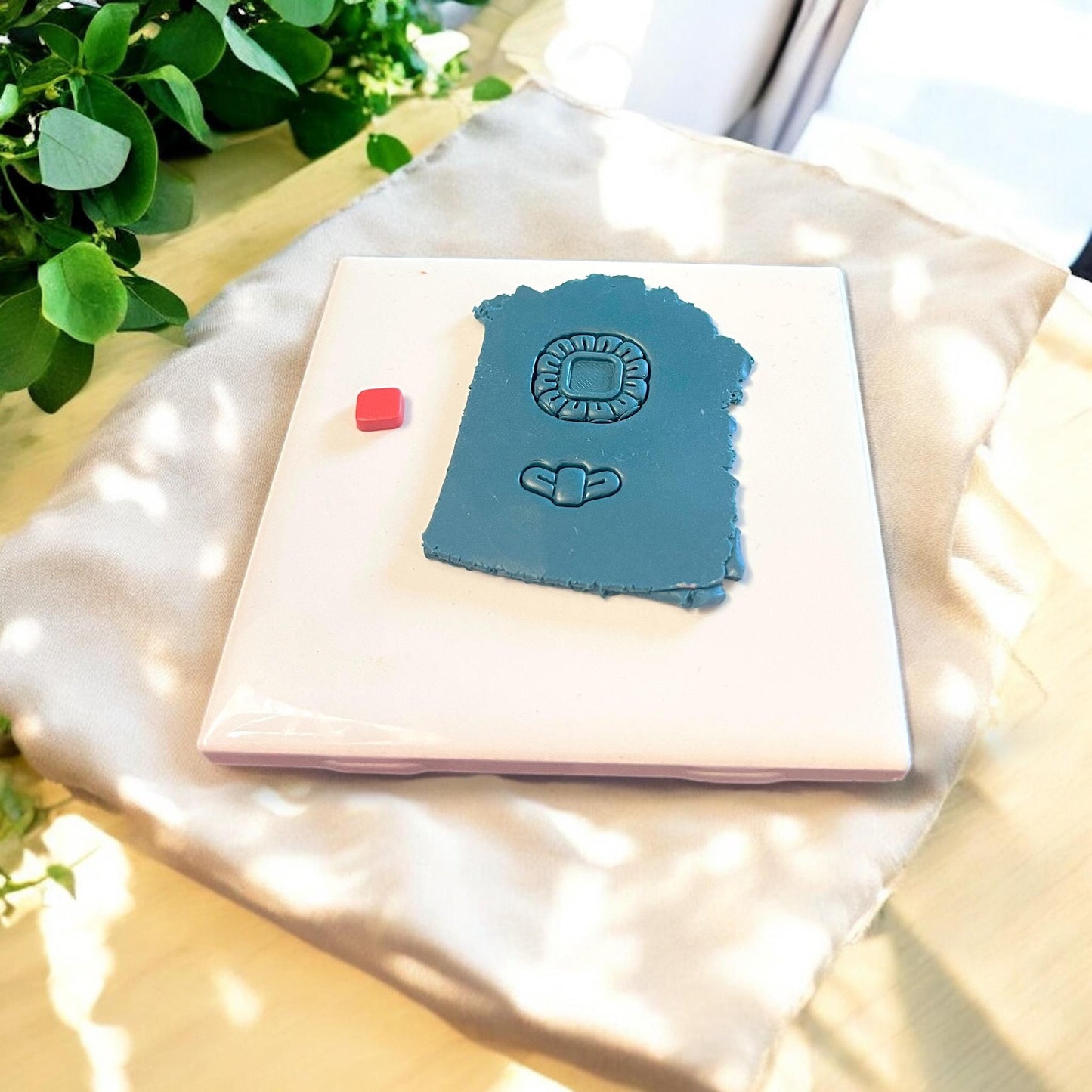 Polymer clay sheet showing flower shape cutter impression with center gem-like detail and petal outline design