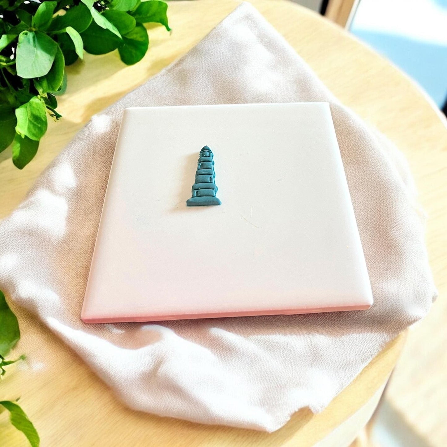 Completed polymer clay earring in the shape of a lighthouse, highlighting intricate details.