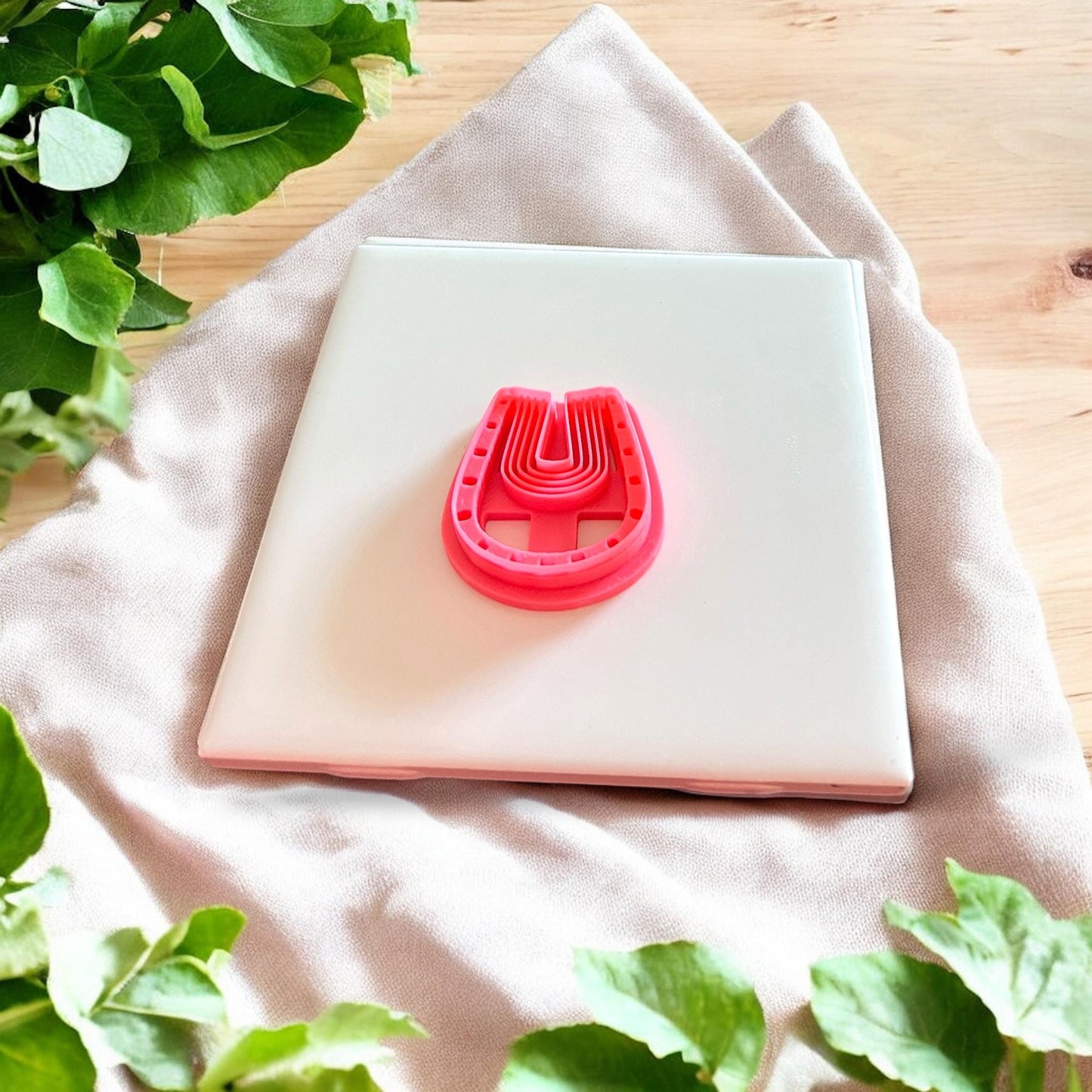 Closeup of pink 3D printed polymer clay cutter in arch shape with ridge detail and dotted edge