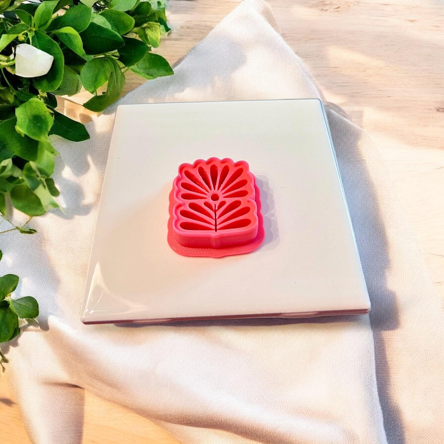 Scandinavian floral clay piece and red 3D cutter side by side for polymer earring making