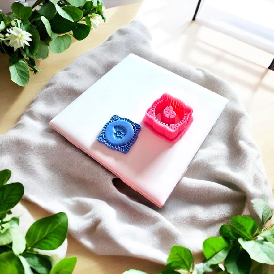 Polymer clay seashell earring piece and red oval cutter beside each other on tile, highlighting embossed detail