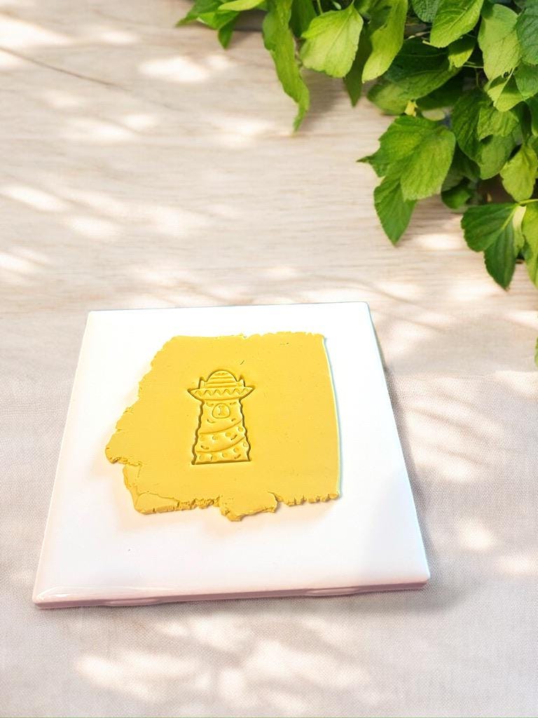 Festive llama-shaped polymer clay cutter pressed into red clay slab, showcasing detailed holiday design.
