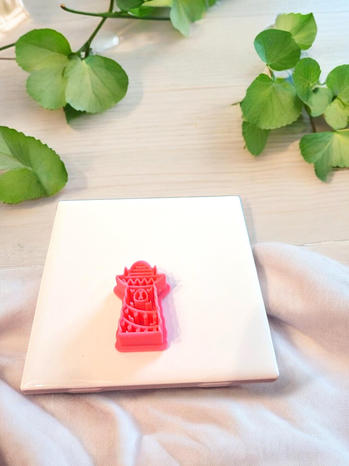 Red polymer clay cutter in festive llama shape placed on soft beige surface, emphasizing design details.