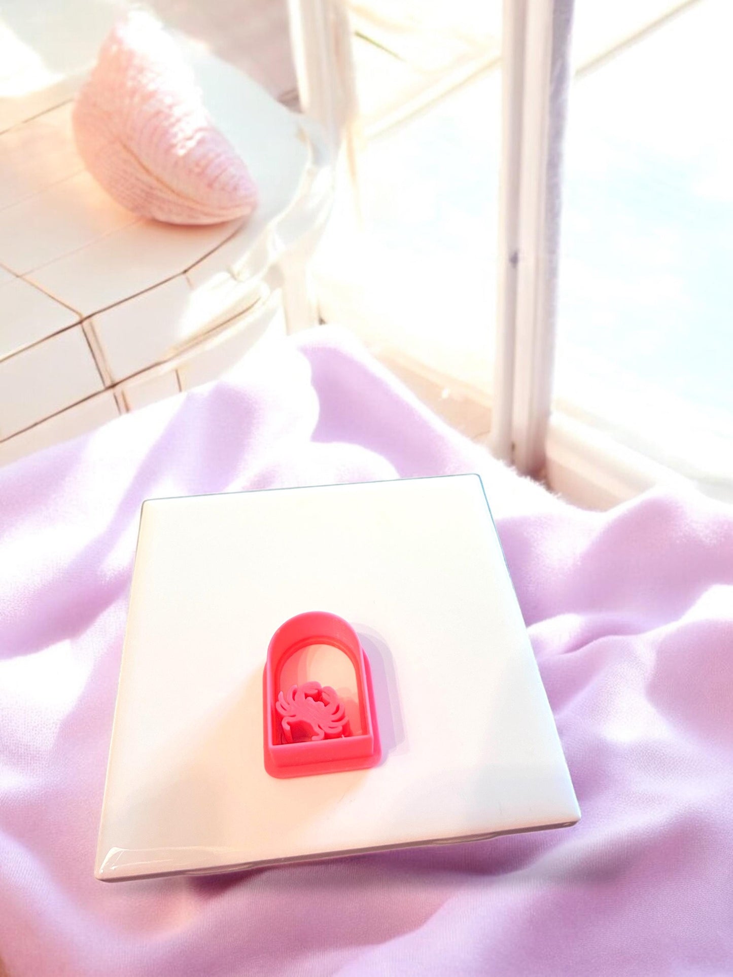 Red arch-shaped cutter with a crab center design, set on a bright white tile for clean product display.