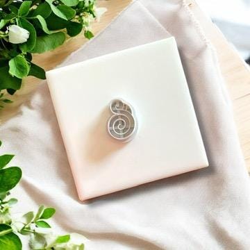 Gray twisted flamingo clay cutter displayed on a white ceramic tile, ideal for polymer clay jewelry.