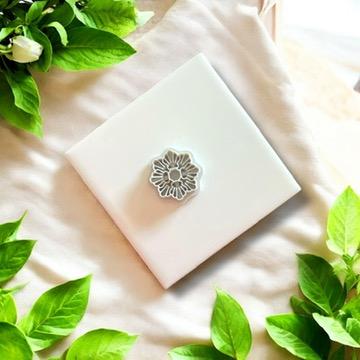 Gray seashell wreath clay cutter displayed on a white ceramic tile with greenery, perfect for summer jewelry projects.