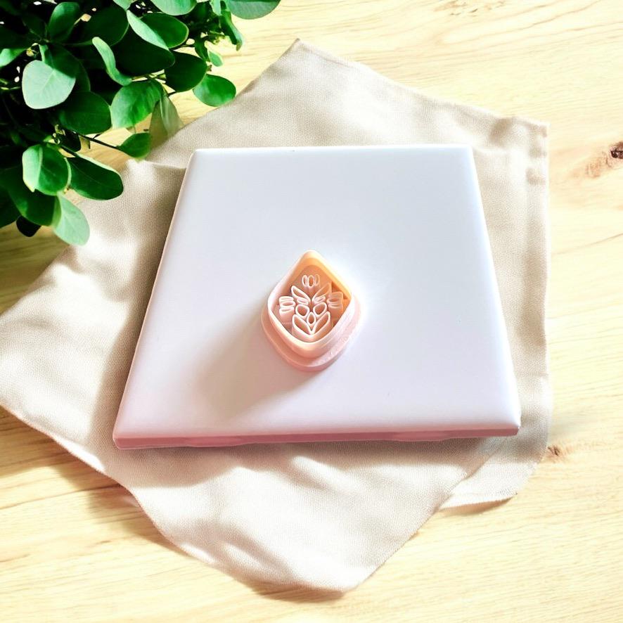 Pink pastel cutter showcasing Scandinavian floral design with a molded clay piece on a white ceramic tile