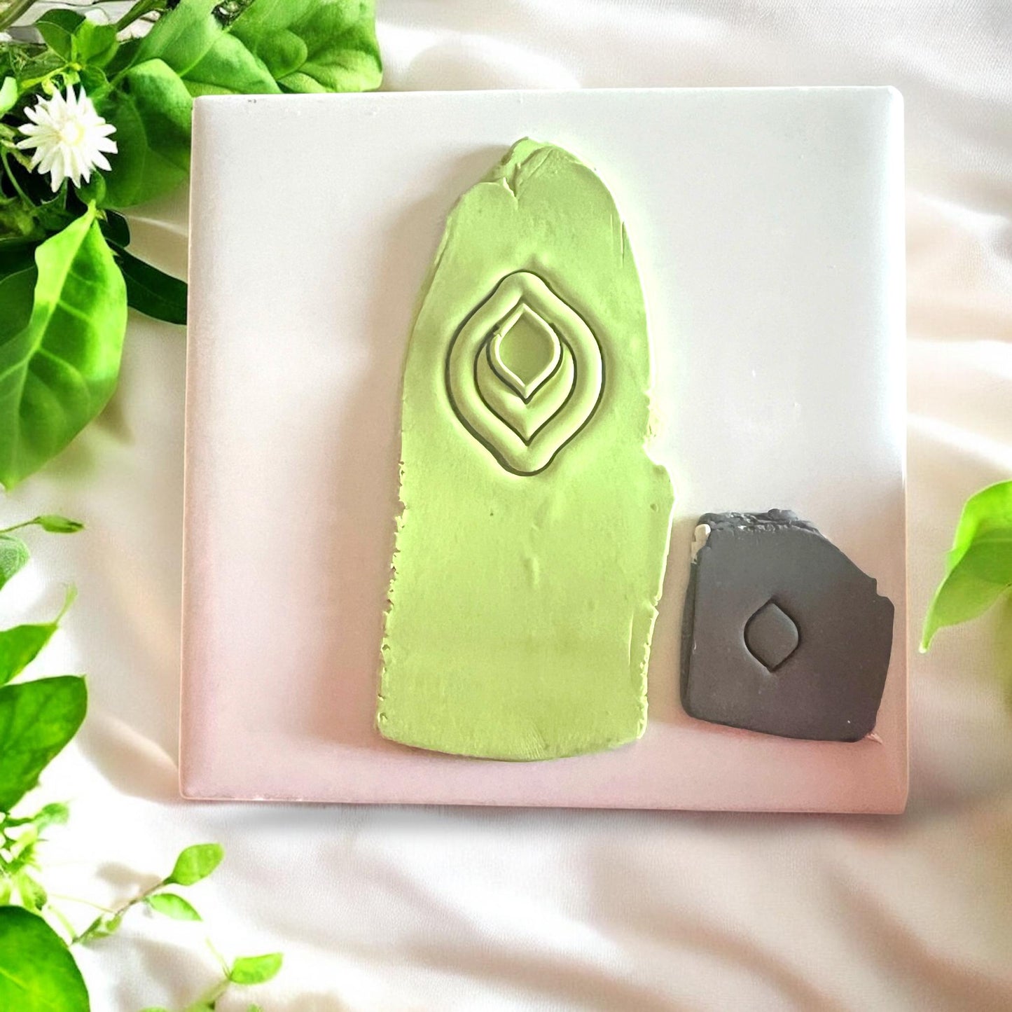 Green clay slab with jewel drop cutter impressions displayed under bright lighting on a white tile background