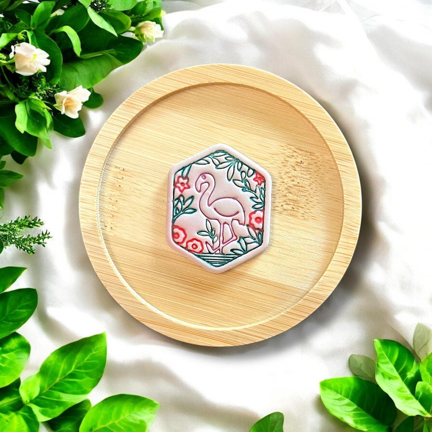 Finished garden flamingo charm, painted and displayed on a bamboo tray with floral details and vibrant colors.