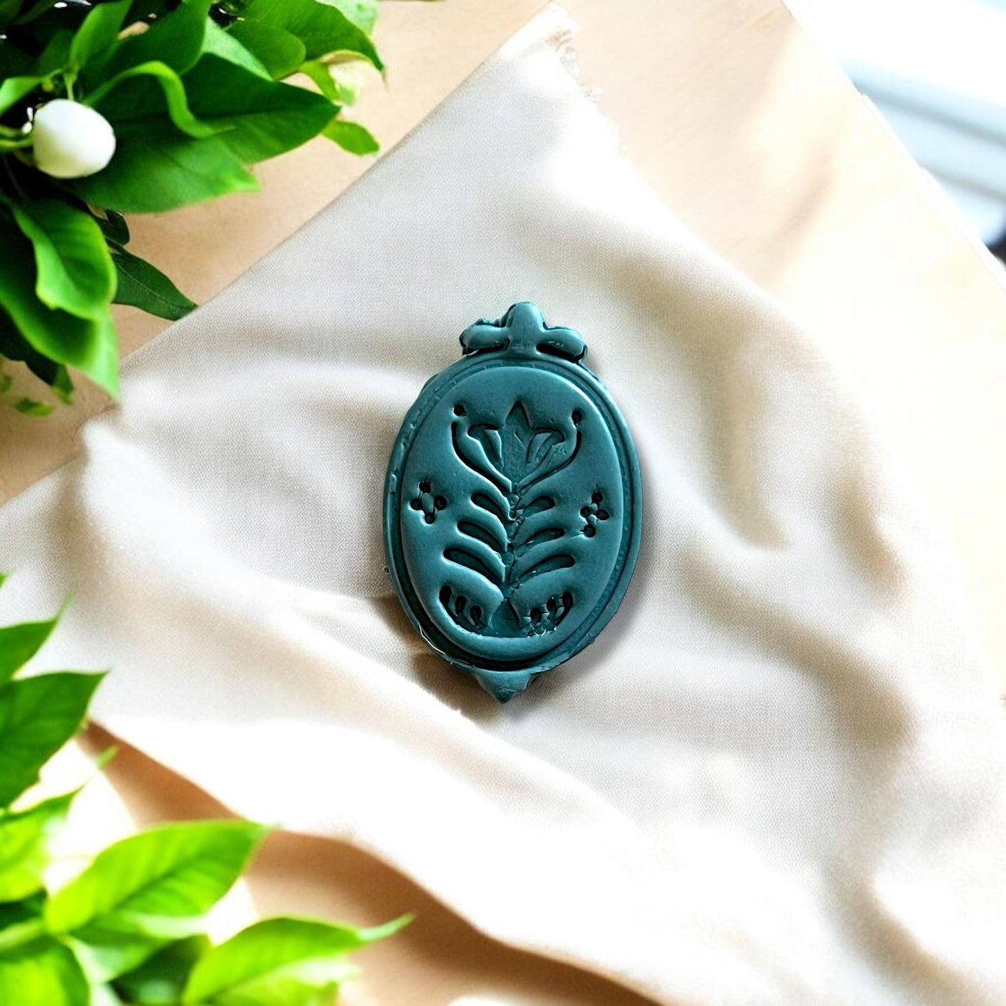 Close-up of teal folk flower charm on neutral background