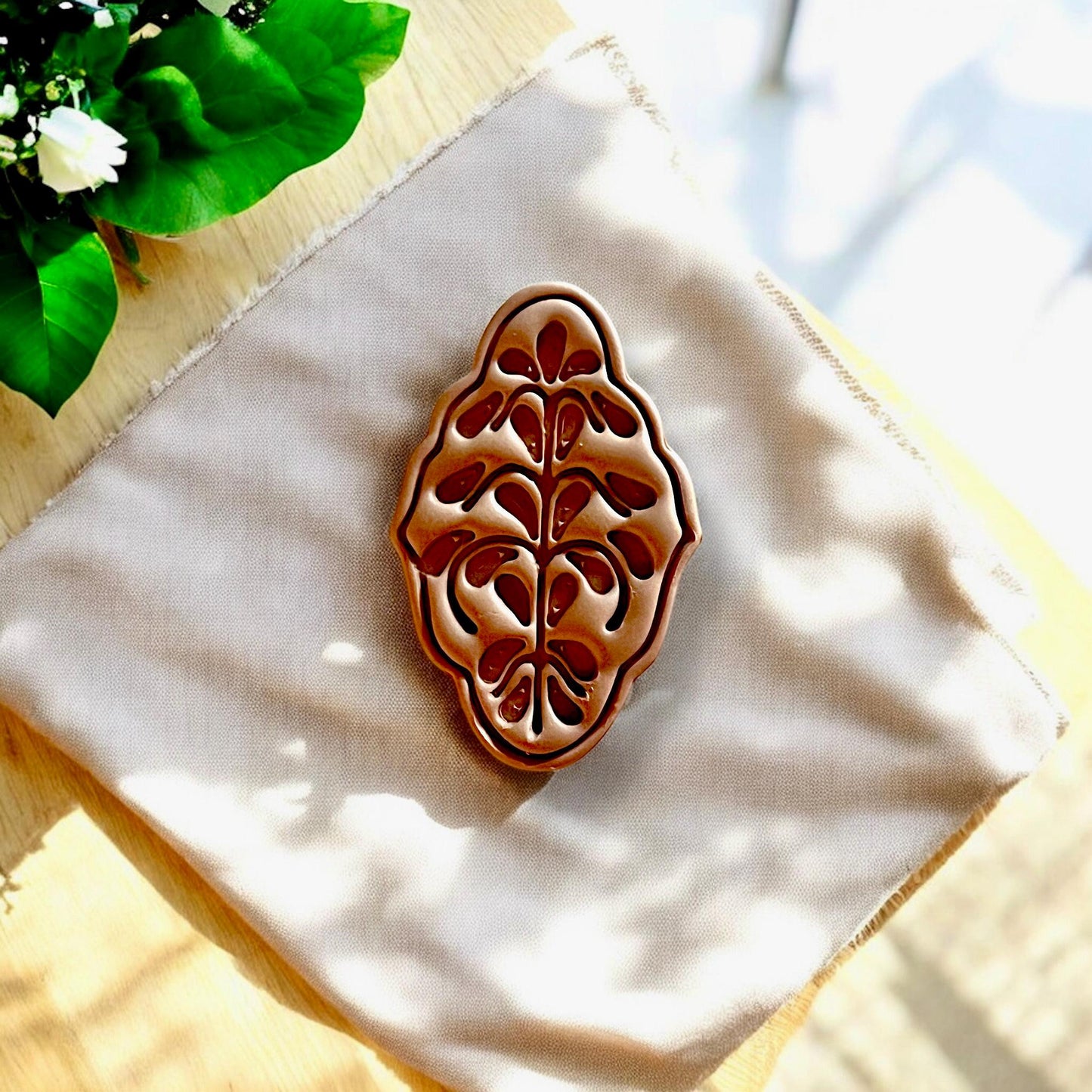 Finished clay earring piece with boho Nordic floral cut on natural fabric