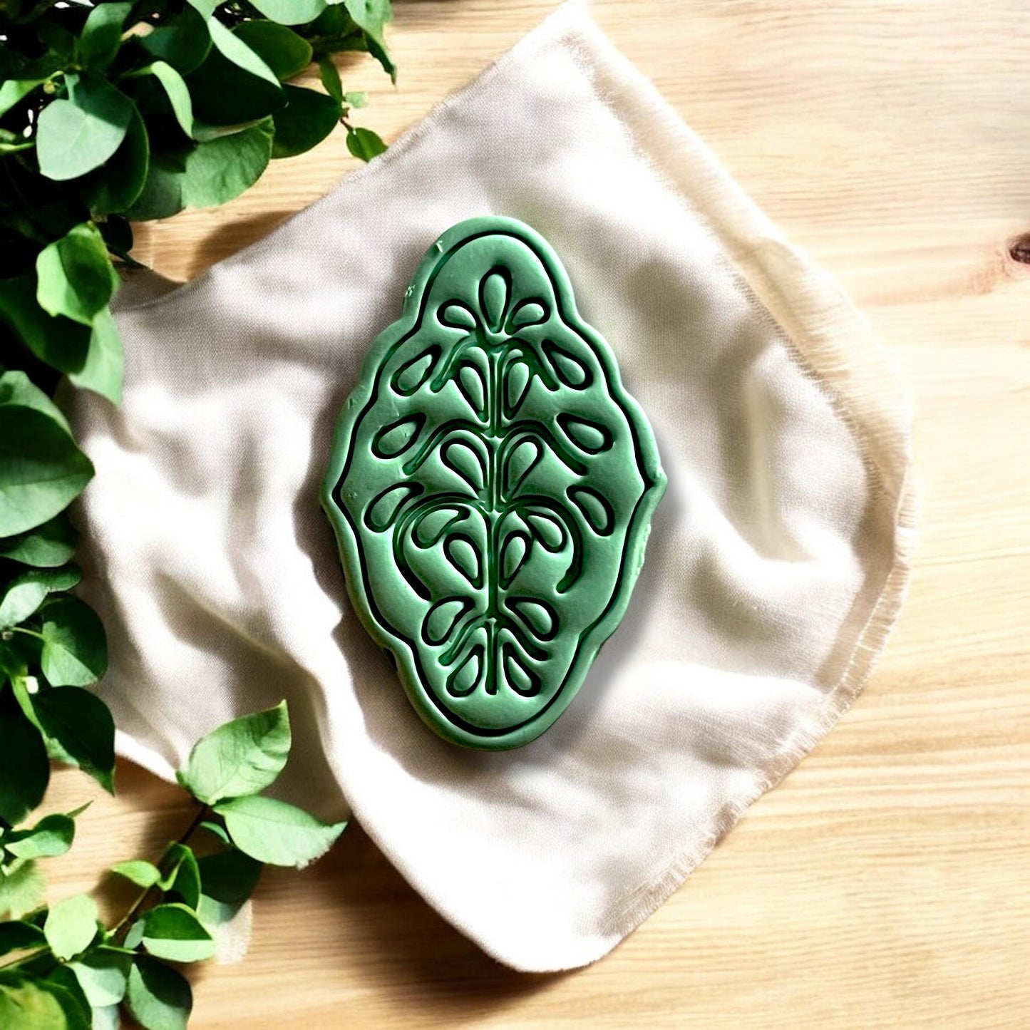 Large deep green floral design cutout displayed on fabric backdrop