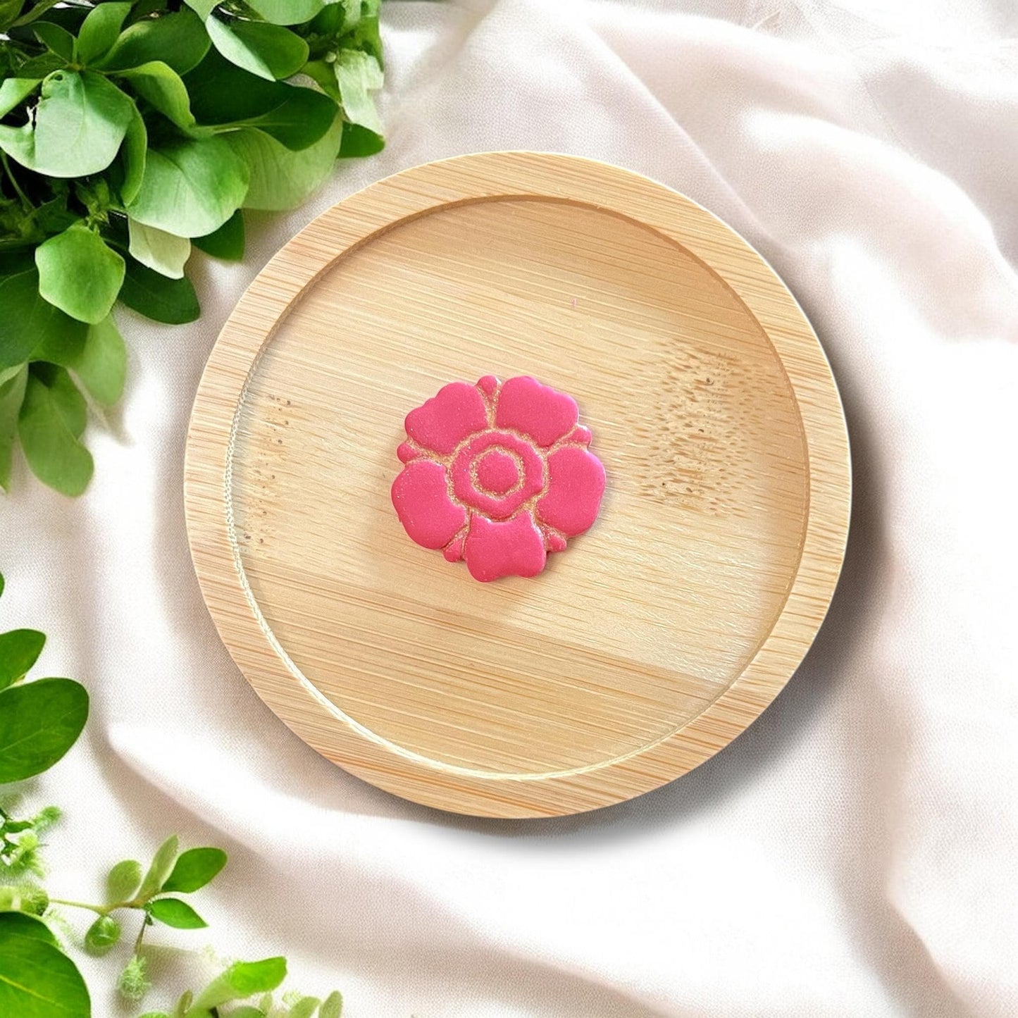 Finished anemone clay flower styled on a bamboo tray with leaf props