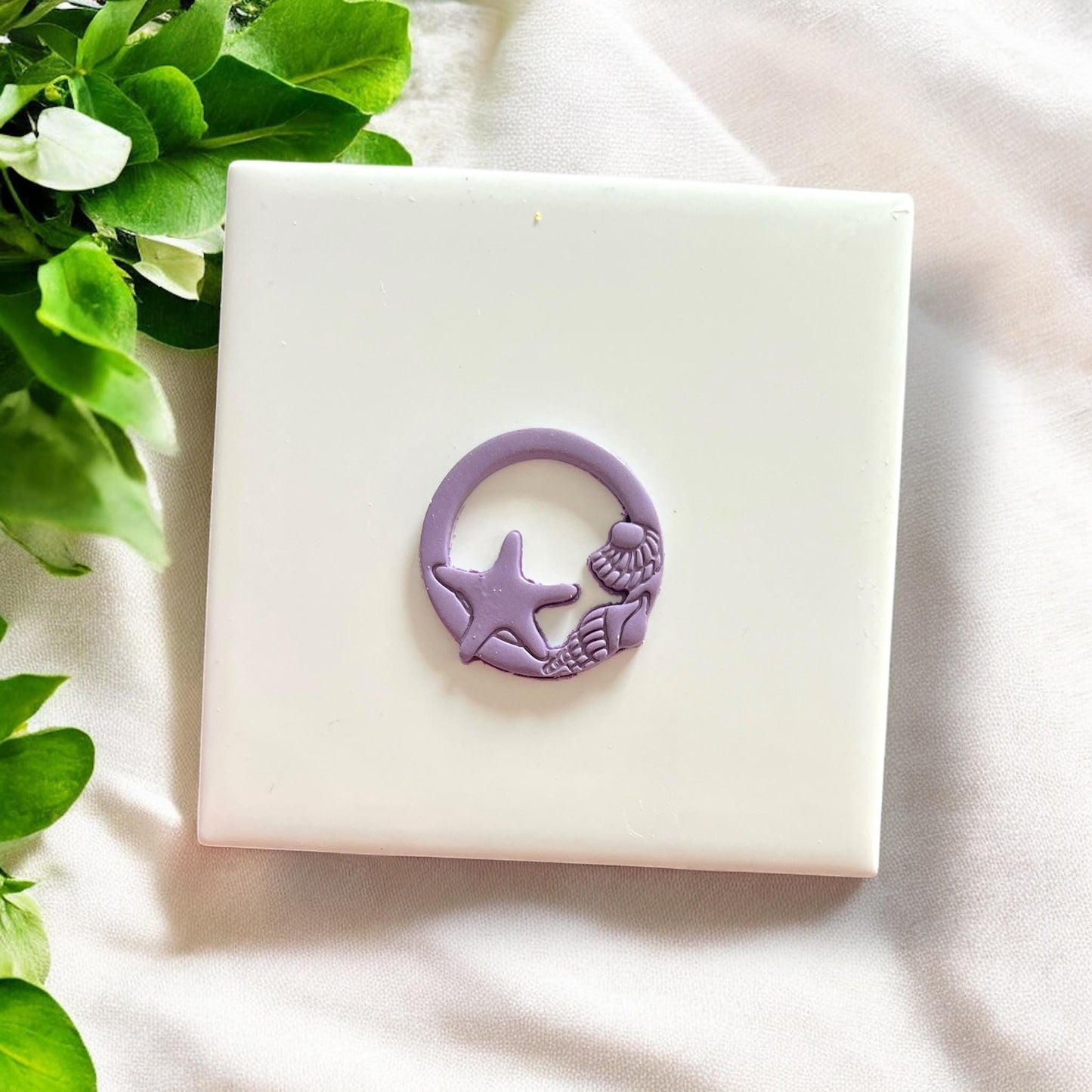 Finished purple clay piece shaped with seashell circle cutter showing clean coastal-themed cut and detail