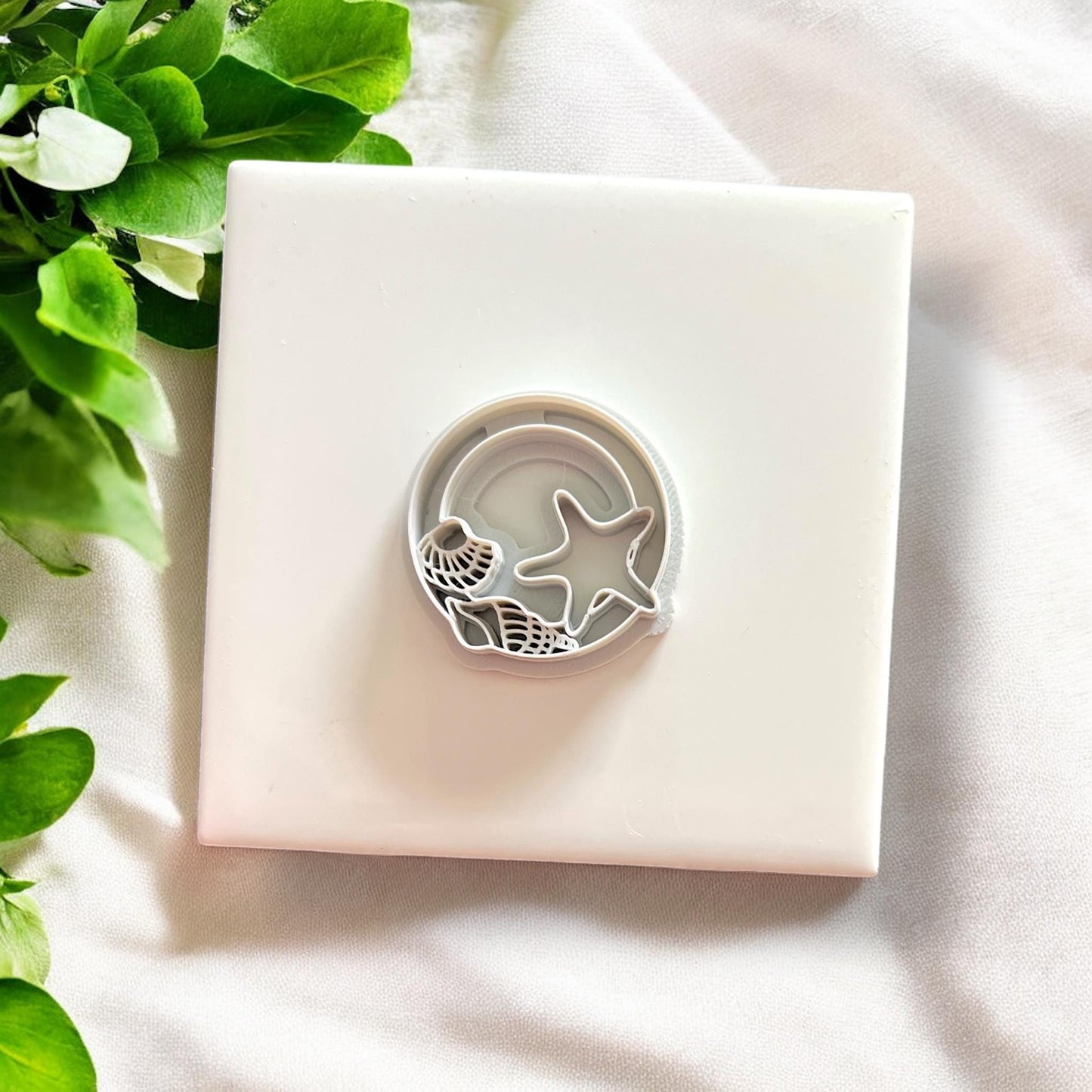 Top-down view of both parts of the seashell circle cutter placed together over a white background