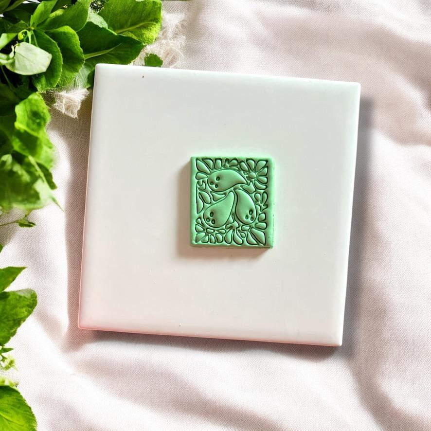 Finished polymer clay earring piece in ghost Matisse shape with spooky floral elements on white tile