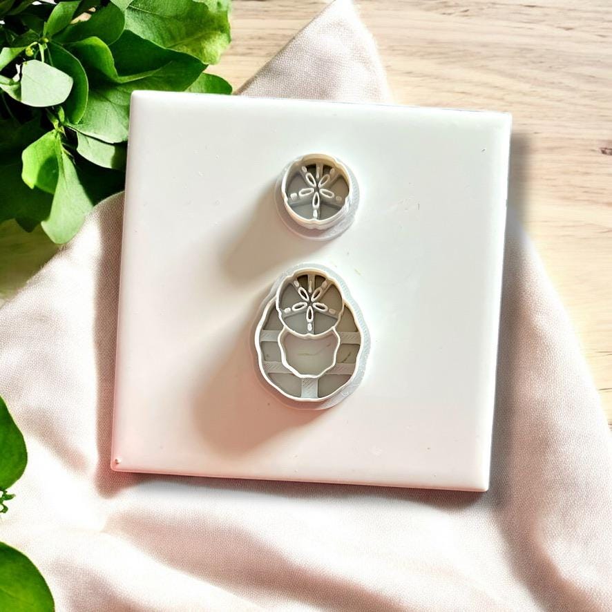 Flatlay of beach-themed polymer clay cutters showing both parts of the sand dollar dangle earring design.