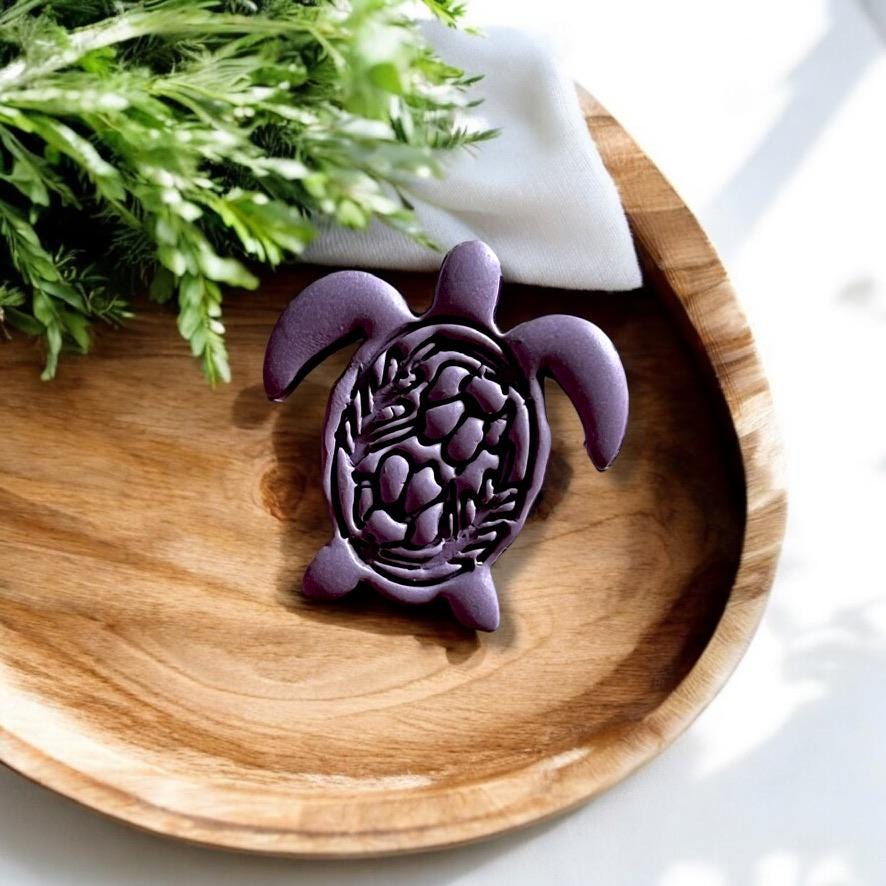 Finished folk art turtle clay design on a wooden tray, surrounded by natural light and greenery