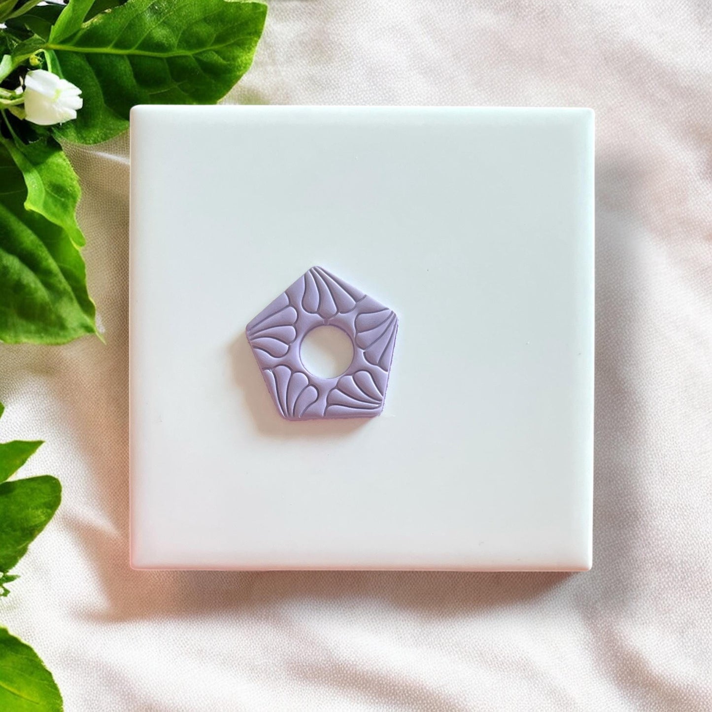 Impression of the floral motif cutter on a slab of polymer clay, showcasing detailed design elements.