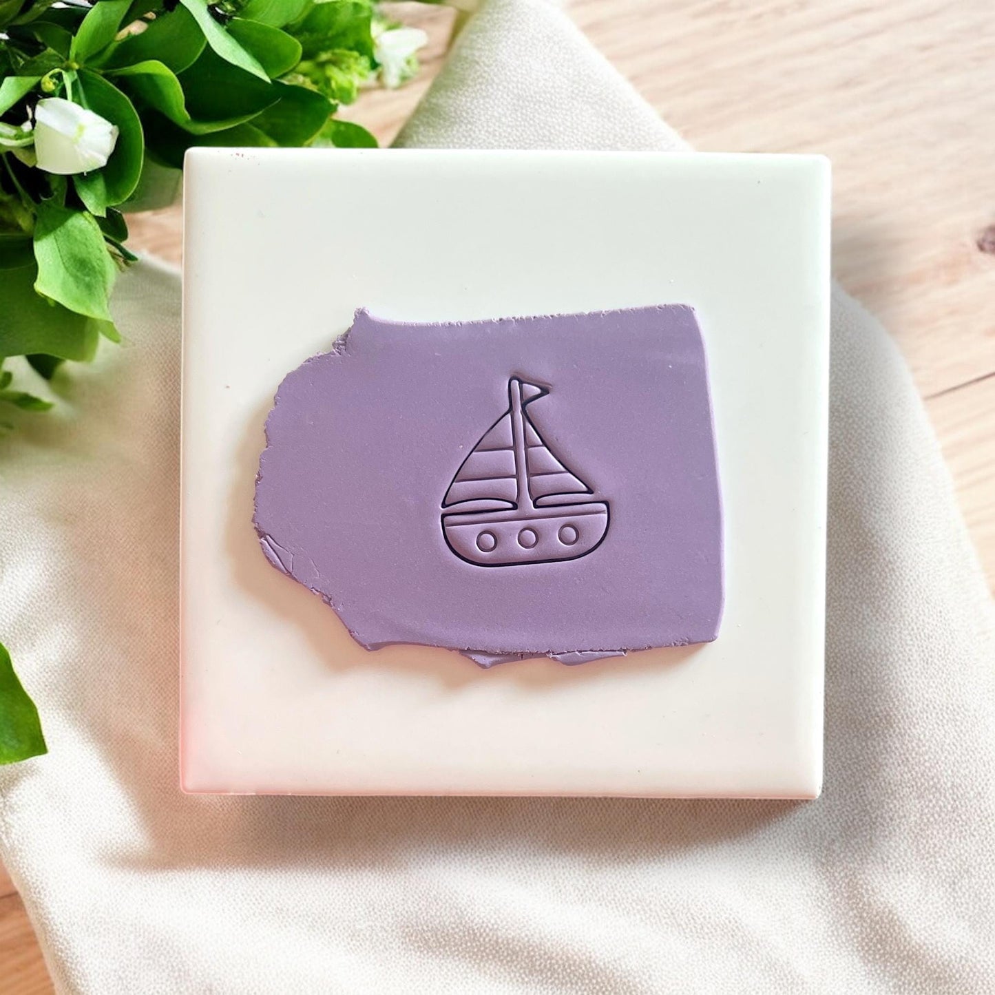 Sailboat-shaped polymer clay cutter on a white tile, perfect for nautical-themed earrings and coastal jewelry making.