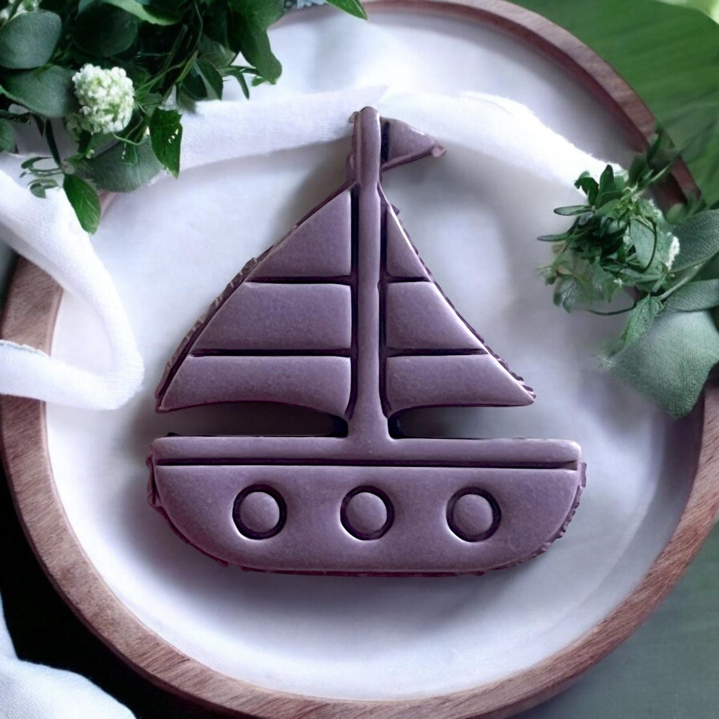Finished sailboat clay piece on a wooden board, ready for jewelry making or decoration.
