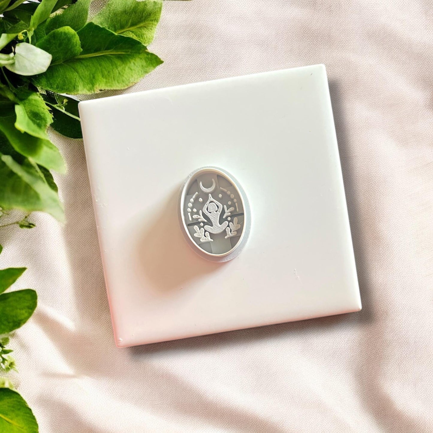 Cutter alongside a clay cutout of a meditating woman, ideal for boho jewelry designs.