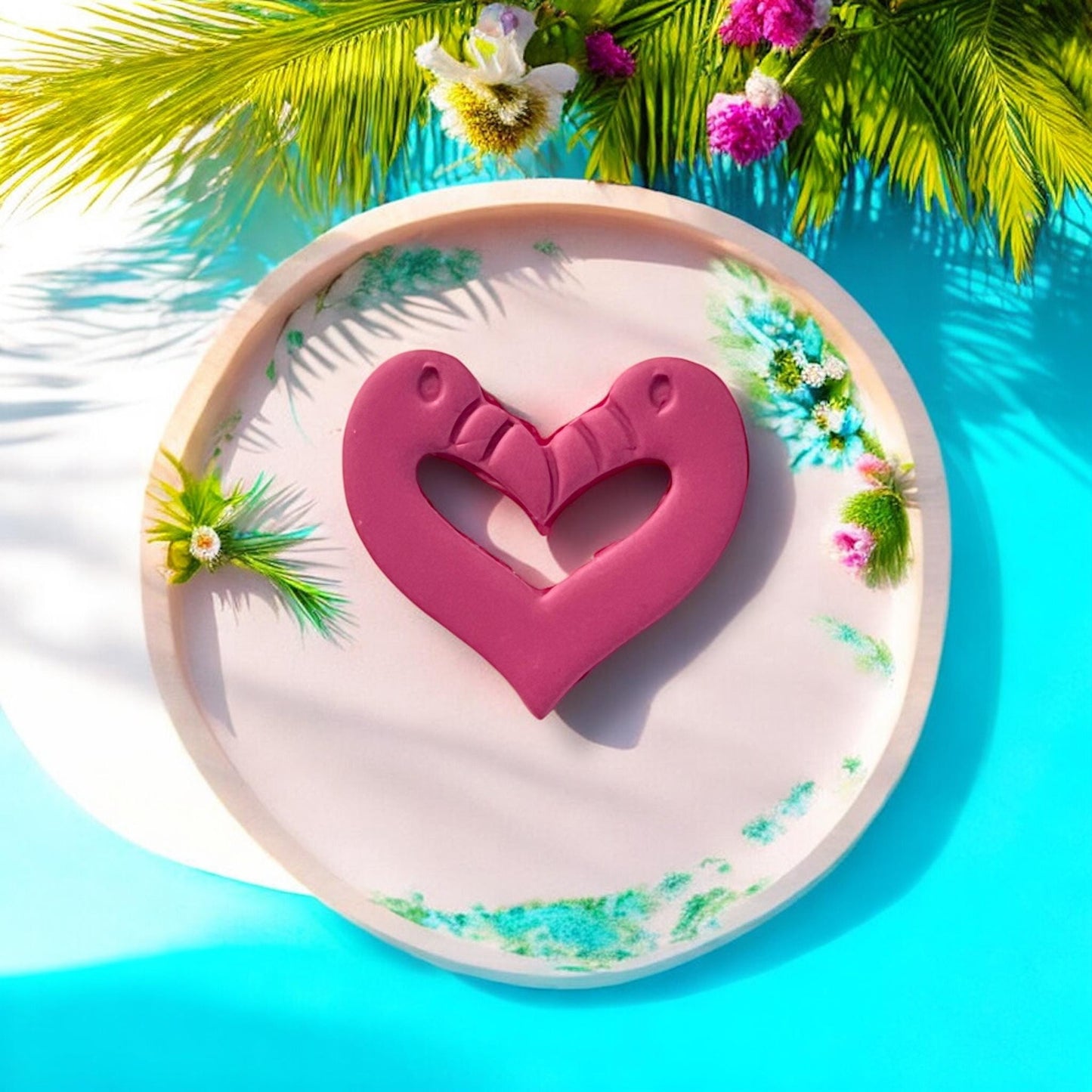 Large flamingo heart clay piece on beach-inspired round tray with floral decor