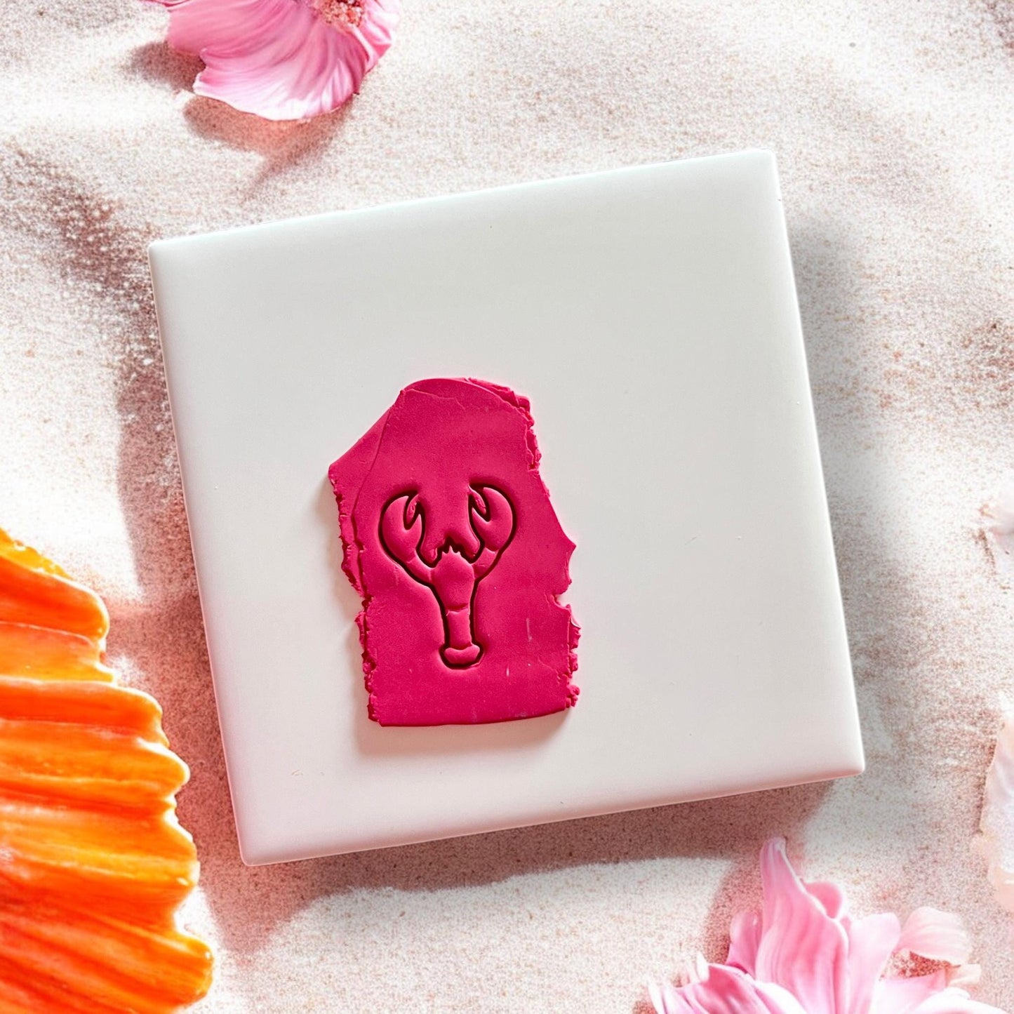 Lobster clay imprint in bright pink polymer clay on a white tile