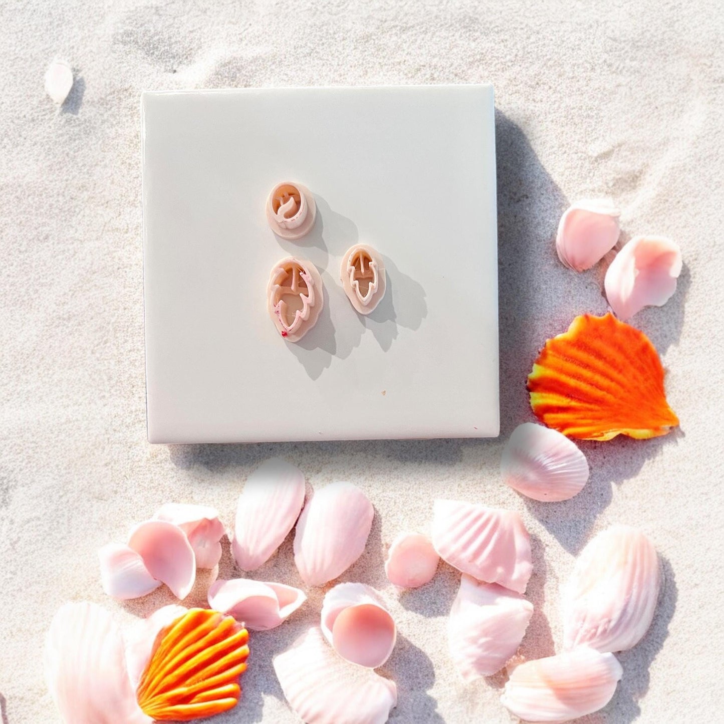 Three flamingo cutters shown separately on tile with seashells