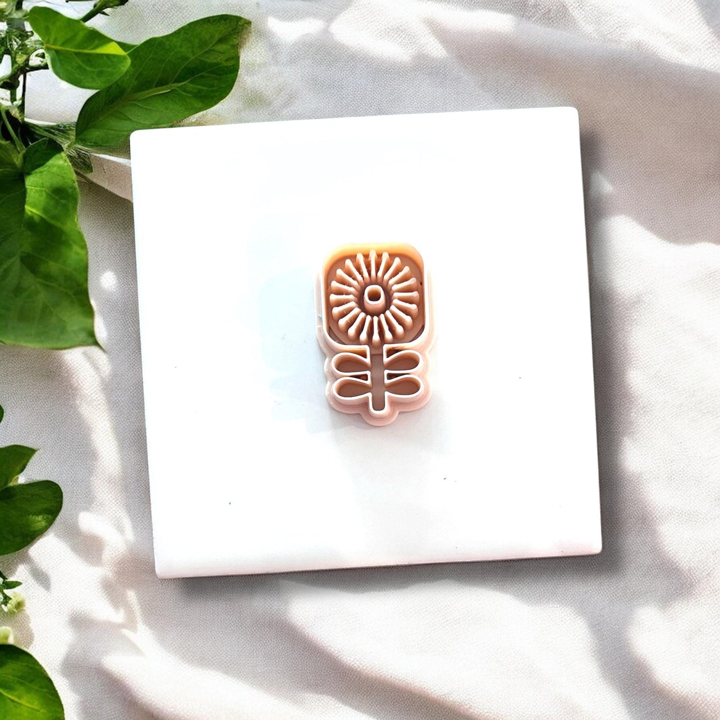 Scandi flower cutter shown on white tile with leafy green decor