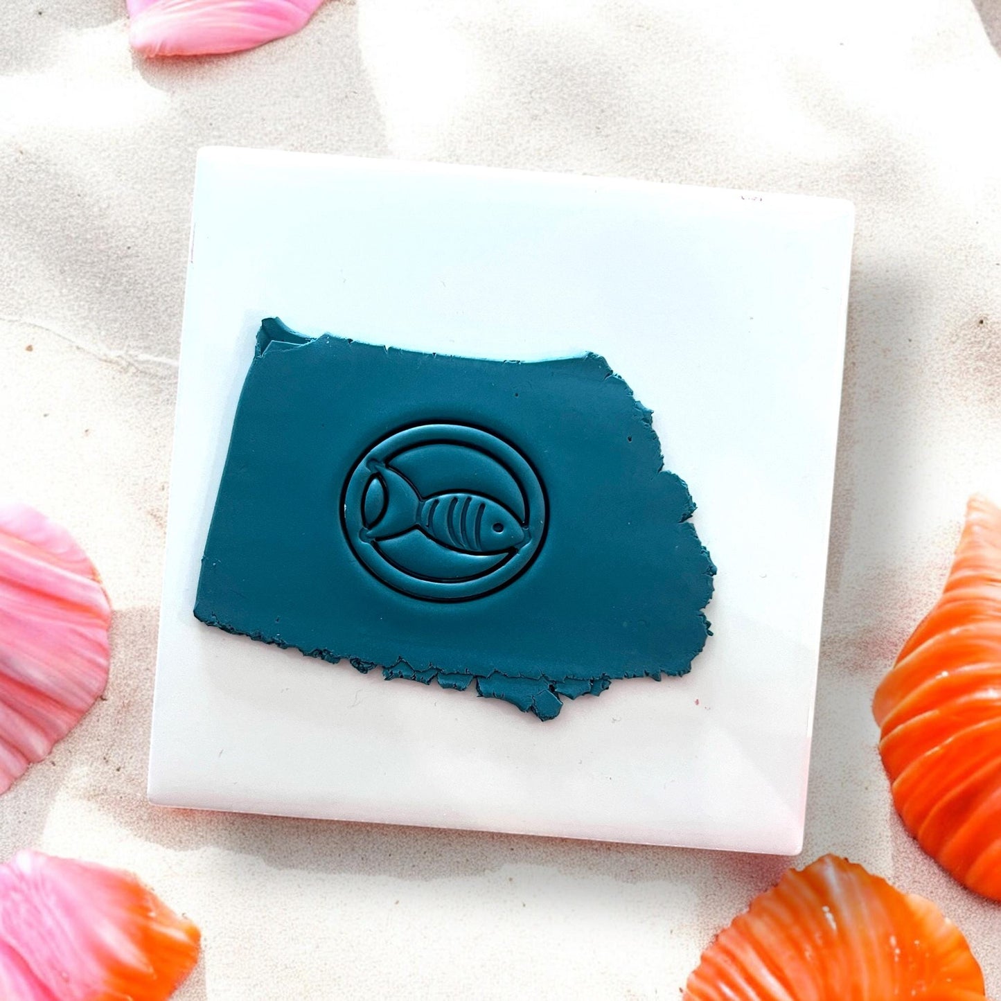 Blue clay slab with a fish inside a circle pressed into it