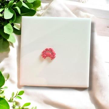 Polymer clay crab charm in pink on white background