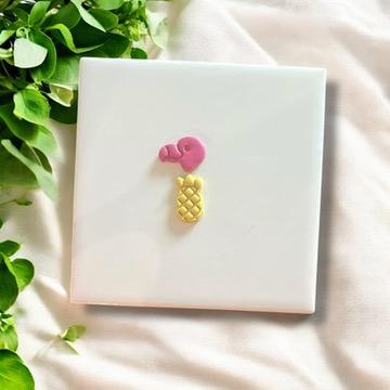Pink flamingo and yellow pineapple clay charms on white background