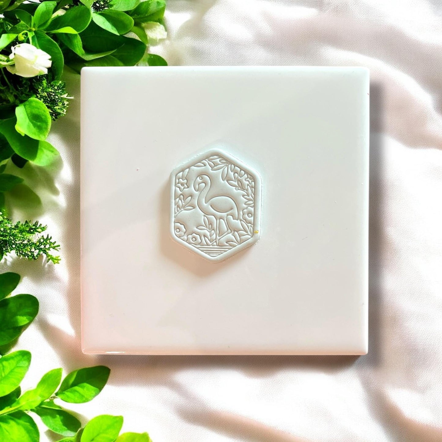 Finished garden flamingo charm displayed on a white tile with floral detailing.