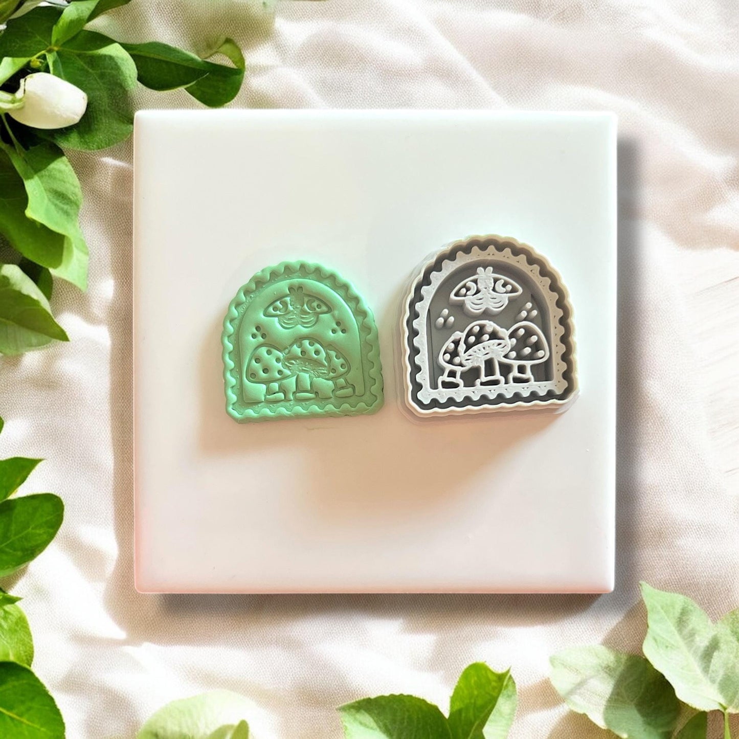 Side-by-side view of green clay piece and detailed gray mushroom moth cutter on a white background.