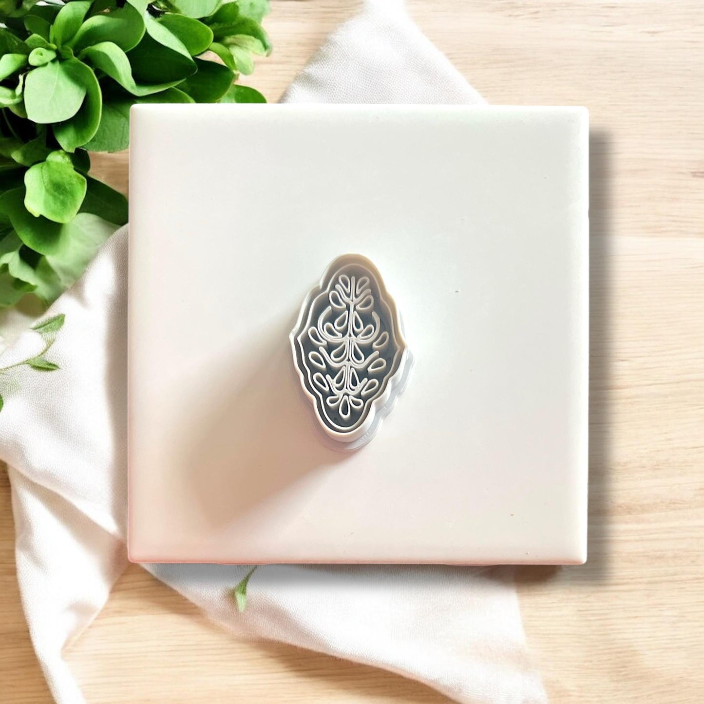 Debossed floral polymer clay cutter shown alone on white tile