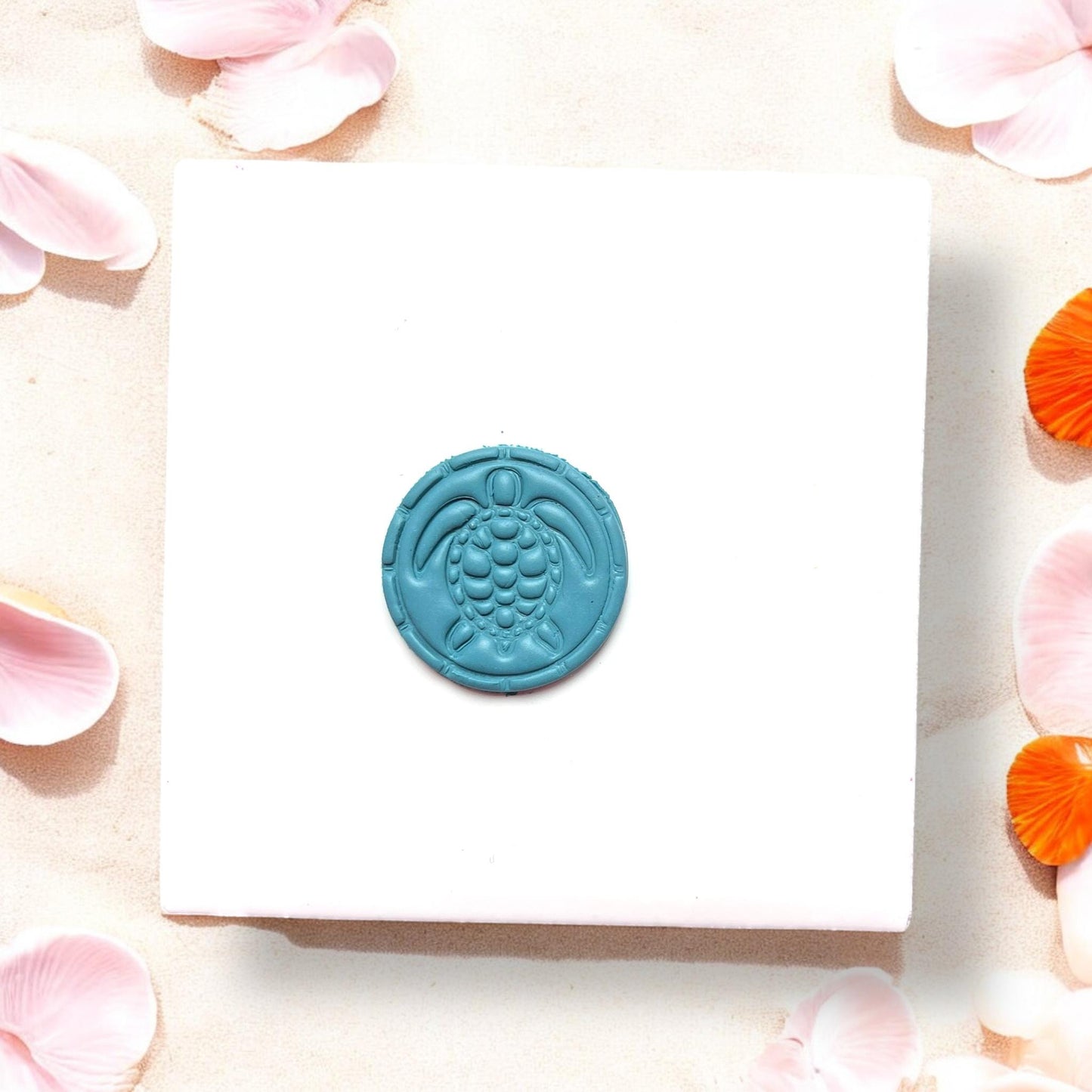 Finished sea turtle clay piece on a white tile with beach petals