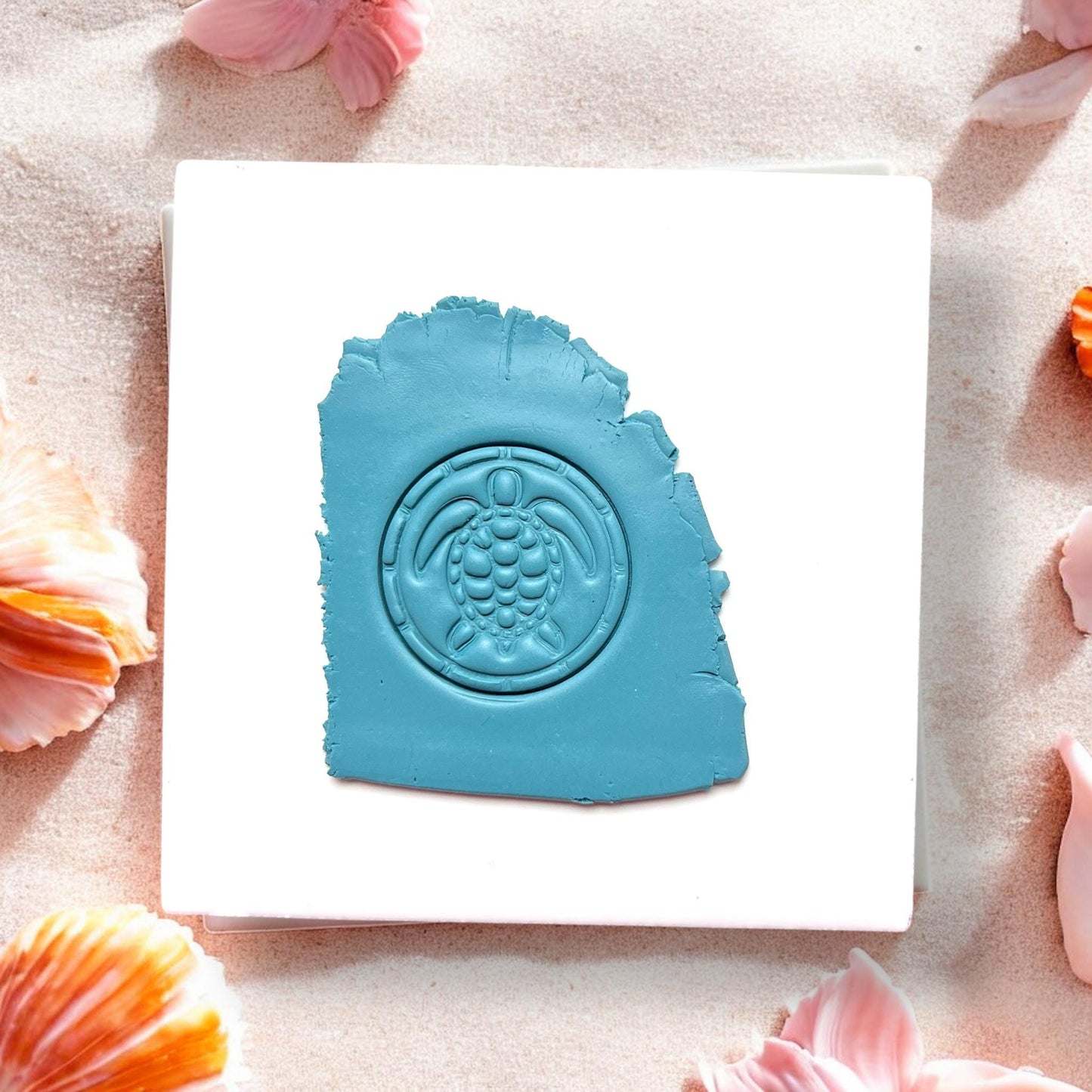 Sea turtle clay impression in blue polymer clay on a tile with shells