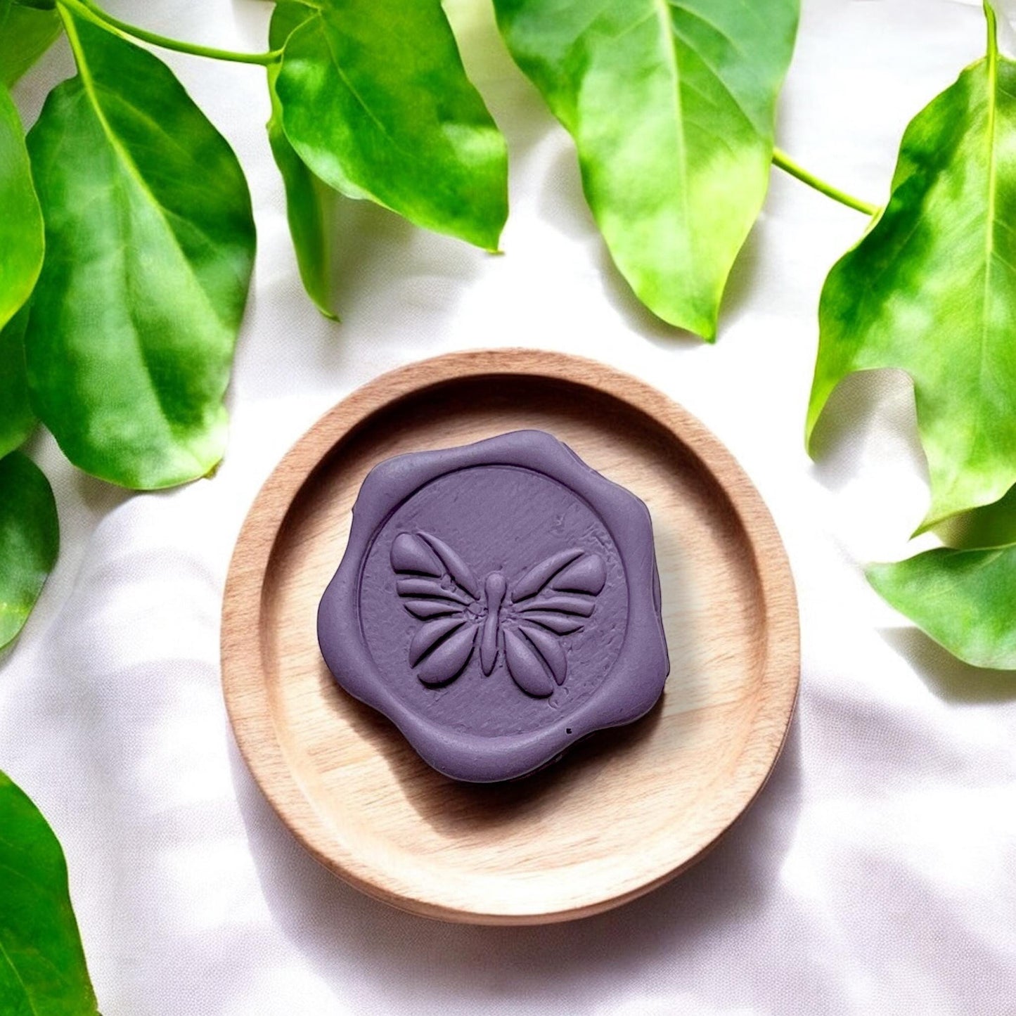 Close-up of finished purple butterfly stamp in wax seal shape on round wooden dish