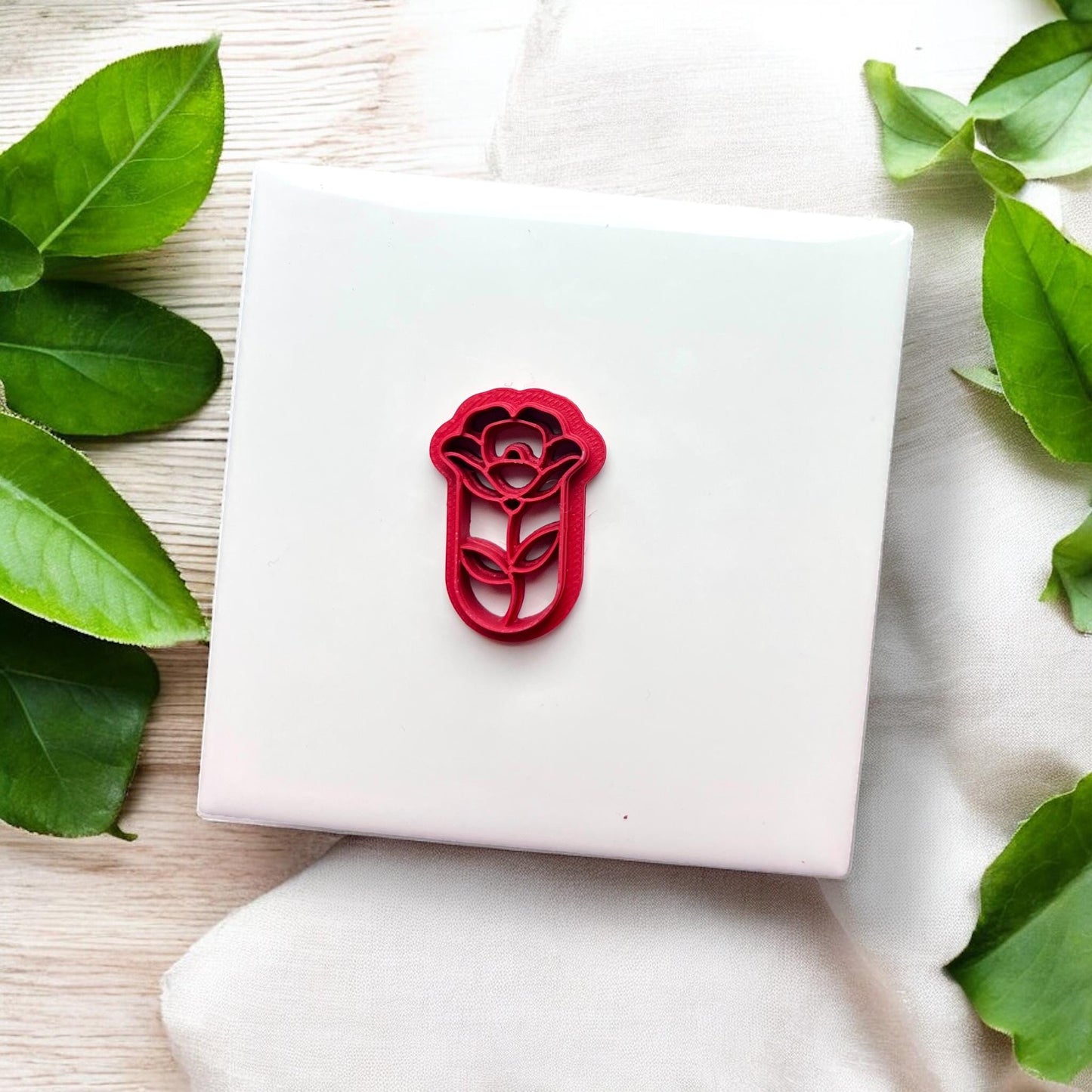 Top view of red flower teardrop cutter on white tile