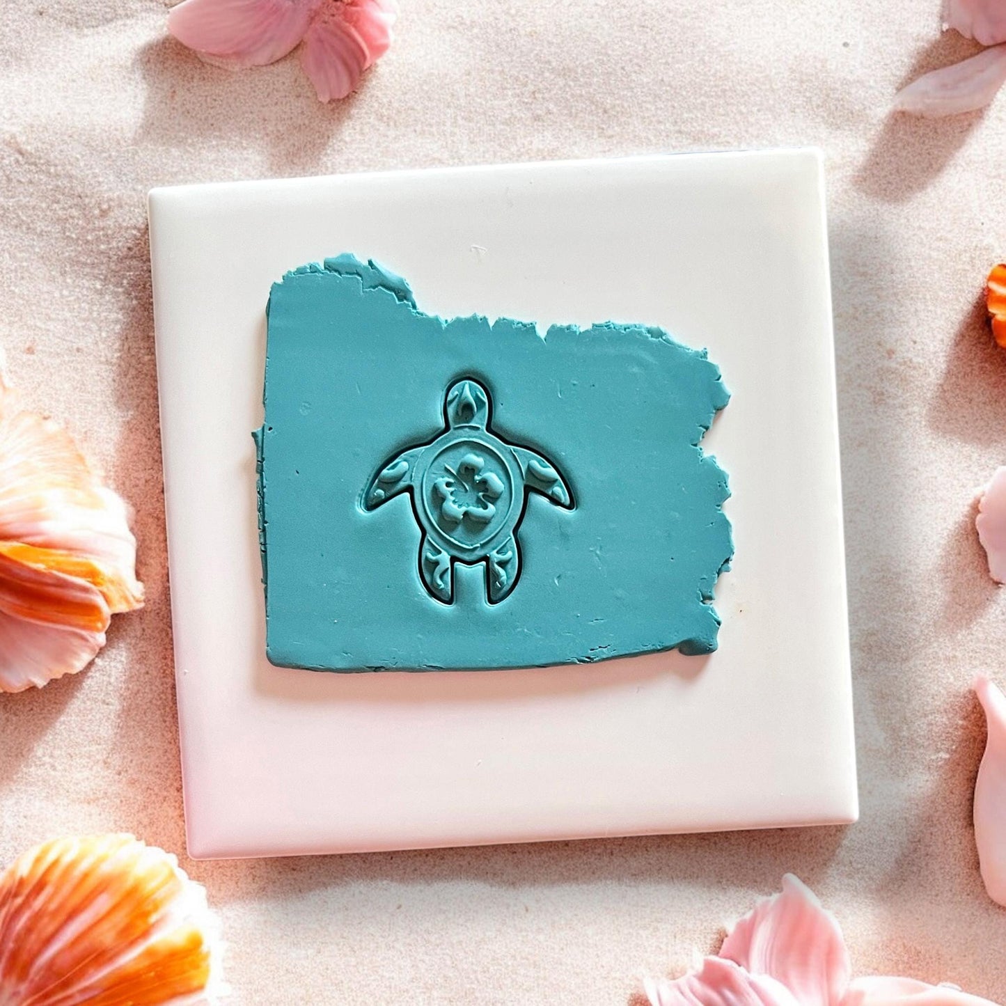 Tropical hibiscus sea turtle clay design on white dish in beach sand