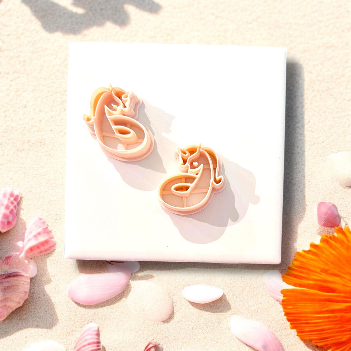 Pair of unicorn floatie clay cutters on beach backdrop